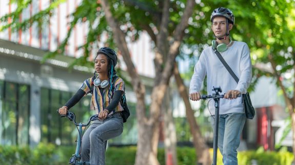 © Envato Elements – SpaceOak Ein Mann und eine Frau tragen einen Helm auf E-Scootern