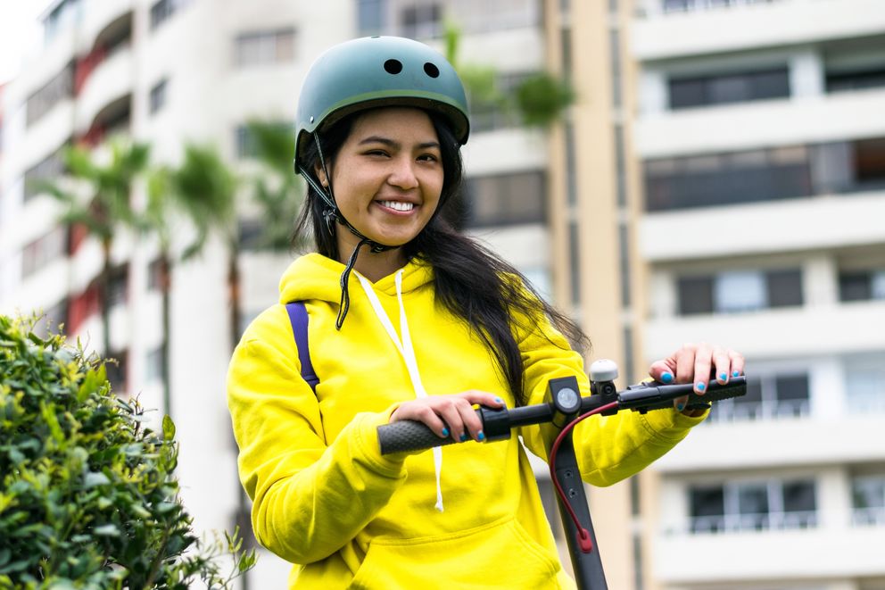 Frau trägt Helm auf e-scooter